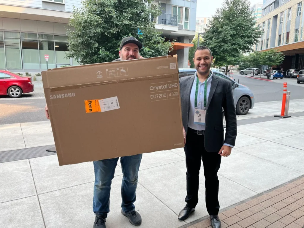 Rose Haven representative and Mack Eltarhoni meeting to transfer donated TV from SEAOC 2024 booth